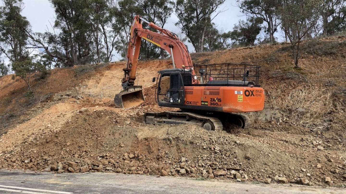 Excavator cutting a road batter