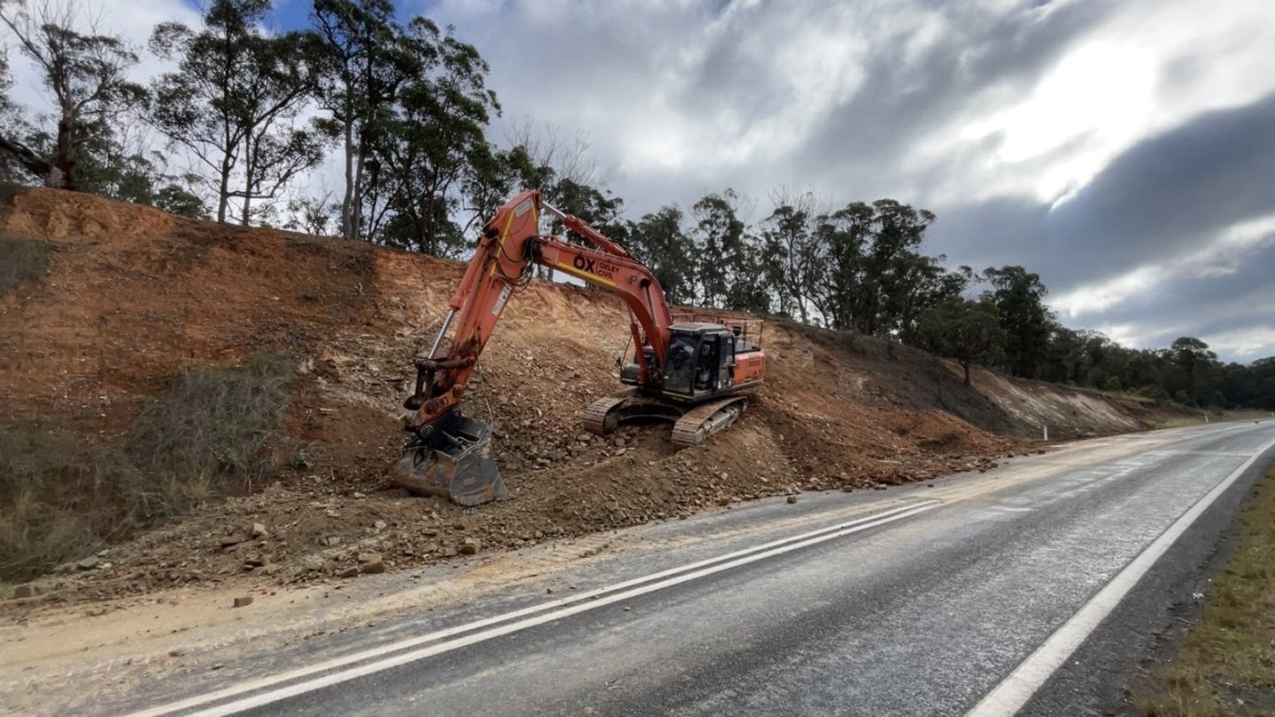 Excavator cutting a road batter
