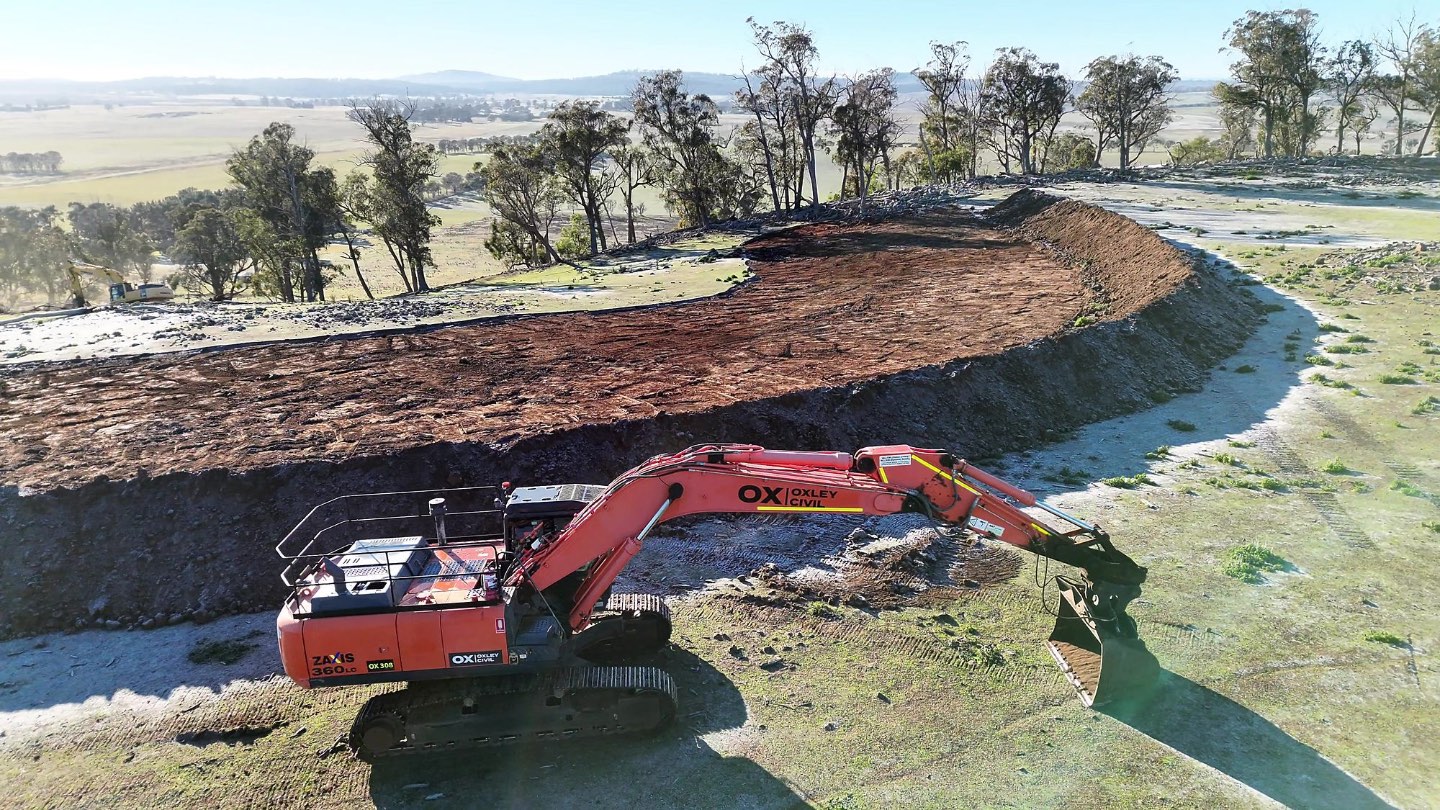 Excavator shaping a bund wall