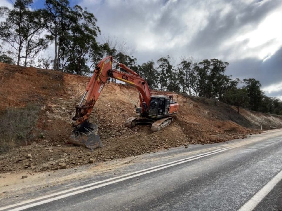Excavator cutting back a road batter